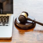 Judge gavel and a laptop, wooden background. Online auction concept